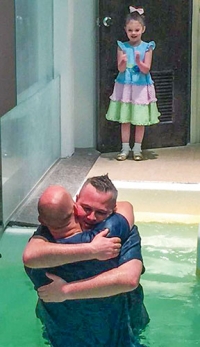 Rivers Clark, age 4, watches as her father, Ron, gives his life to Christ in baptism. 